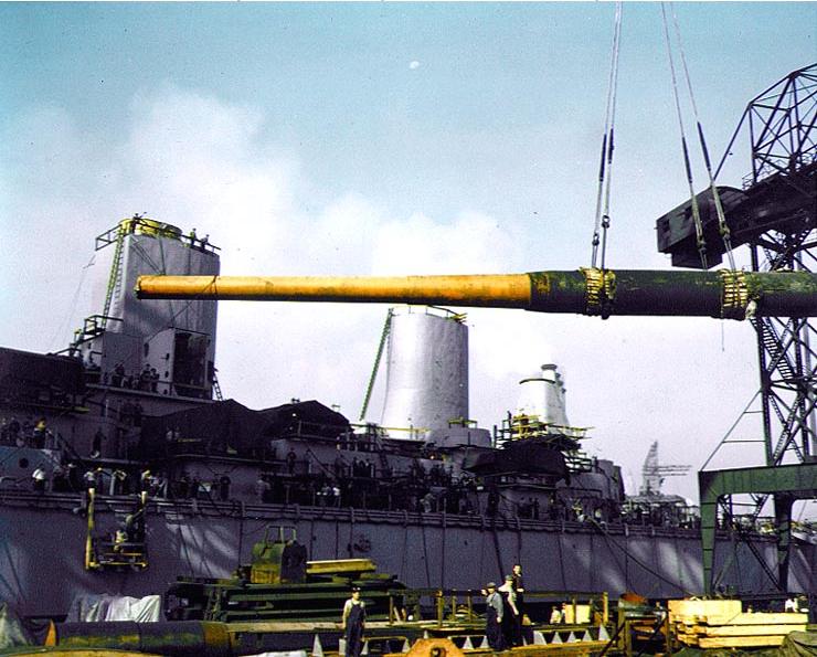 Yard workers, aided by a crane, hoist a 16"/50 Mk VII gun barrel aboard the USS Iowa during her construction in 1942.